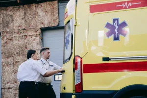Два медика закрывают двери машины скорой помощи