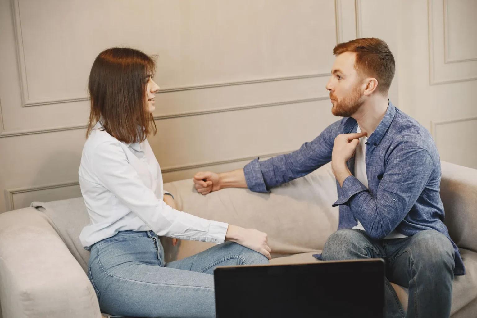 Мужчина и женщина разговаривают, сидя на диване