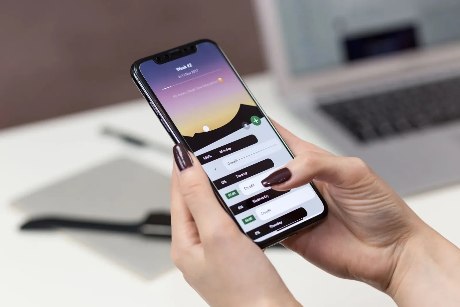 Руки держат смартфон с открытым приложением на фоне ноутбука